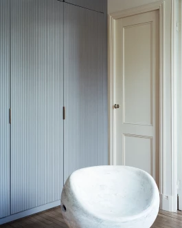 living room with vertical striped cupboards behind Willy Guhl chair 