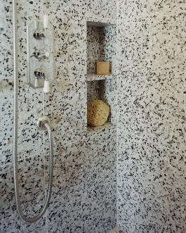 bathroom shower with floor to ceiling terrazzo and classic styled faucets 