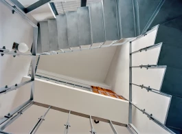 underside view to ceiling of an angular three level staircase void with raw metal stairs and balustrade 