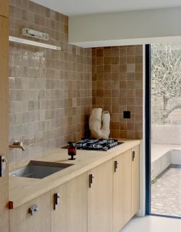an elegant kitchen with clear rough-sawn oak cabinets, artisanal backsplash and a large contemporary glass sliding door leading to a garden 