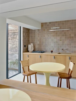 oak and wicker designer chairs by Marolles around a sherbet yellow table by Matti Suuronen, all reflected in a large wall size mirror 