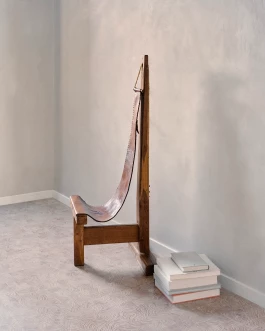 contemplative wood and leather chair by Dominique Zimbacca in a shadowy, off-white space 