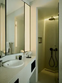 Oblique walled bathroom with a game of panelled reflection and diffused lighting. 