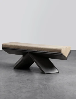 Rhomy bench by Corpus Studio, a cream Cavallino cowhide cushion resting on an angular metallic base of inverted braces, in a pale grey studio