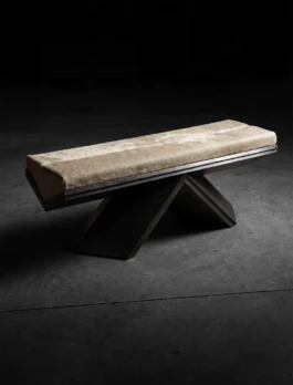 Rhomy bench by Corpus Studio in dramatic low light, its cowhide seat balanced on an inverted V-shaped metallic base