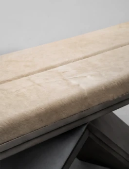 Close-up of the cream Cavallino cowhide cushion of the Rhomy bench, with its central seam and metallic frame